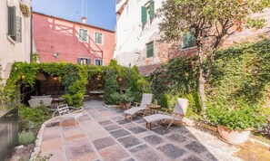 A courtyard with stone flooring, outdoor seating, and greenery. - BEAUTIFUL 3-BEDROOM DORSODURO APARTMENT WITH PRIVATE GARDEN (Venezia)
