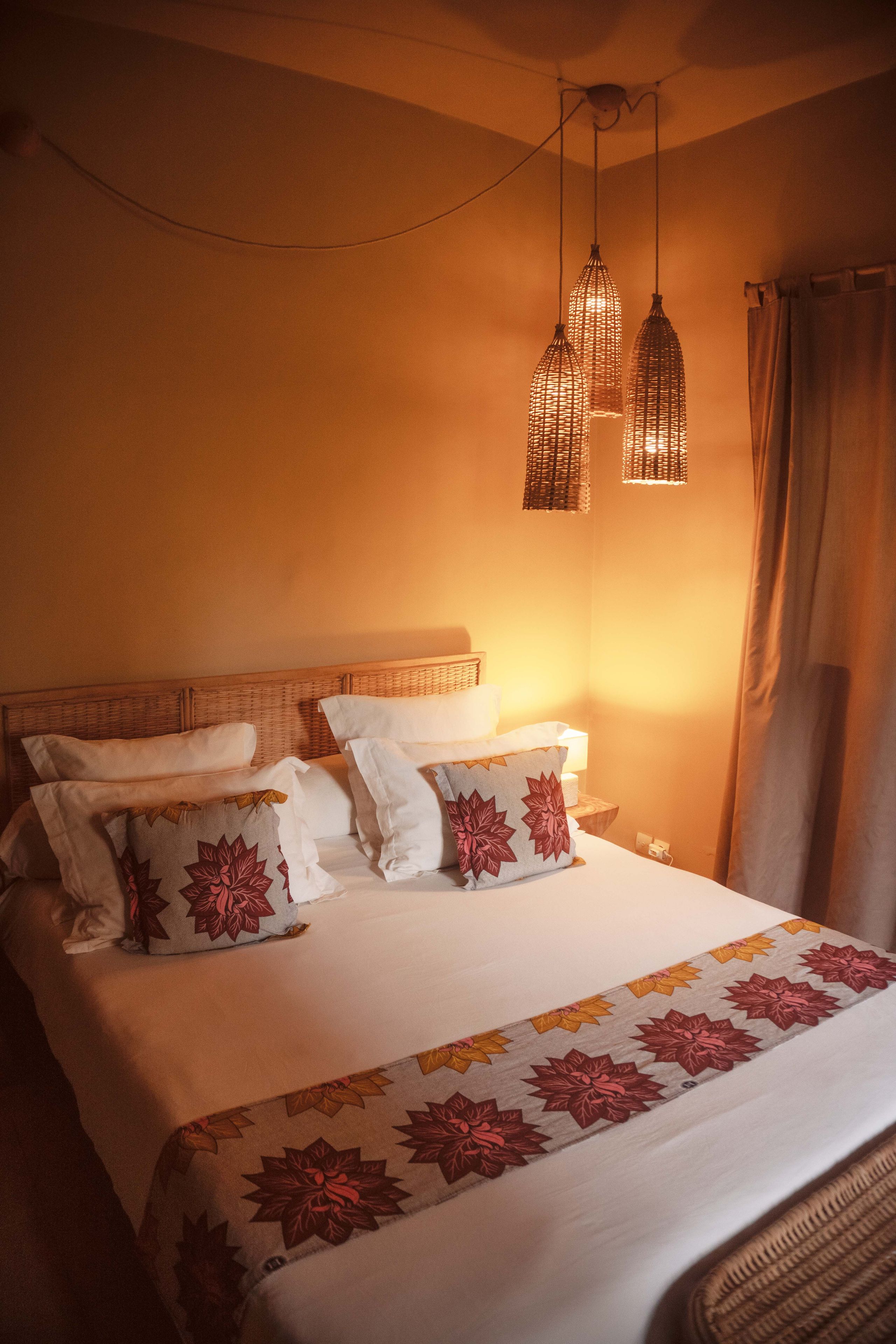A bed with multiple pillows, a bedside table, and hanging light fixtures.