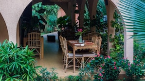 Un espace de restauration en plein air avec une table et des chaises en bois rustique, entouré d’une végétation luxuriante et de plantes.