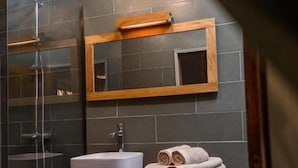 Une salle de bain avec une douche à parois de verre, un lavabo blanc et un meuble-lavabo en bois.