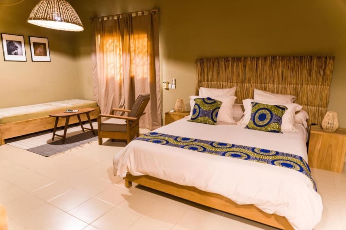 Een slaapkamer met een bed, een stoel, een klein tafeltje en gordijnen.