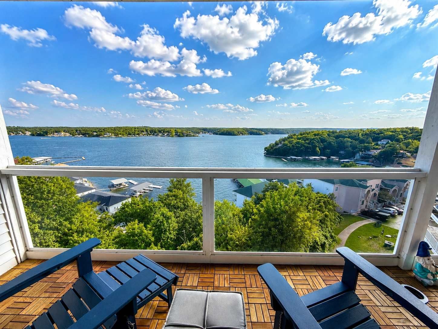 A balcony with a view of a lake, wooden deck, and outdoor furniture.