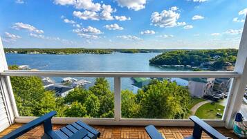A balcony with a view of a lake, wooden deck, and outdoor furniture.