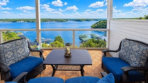 Un patio techado con una mesa y dos sillas, con vista a un lago con barcos y muelles.