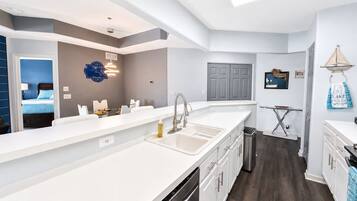 A modern kitchen with a large island, a built-in dishwasher, and a compact layout.