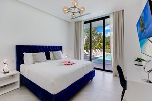 Ein modernes Hotelzimmer mit einem großen Bett, Blick auf einen Swimmingpool und einer Deckenleuchte.
