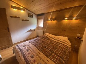 A cozy room with a bed, wooden walls, a window, and wall-mounted lights. - Ski-in/ski-out & foot of the slopes, 3rd floor, balcony, ski locker, 52m², Valmorel (Valmorel)