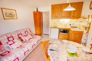 A cozy living room with a sofa and a dining table set for two. - 100m from ski slopes, Ground floor, balcony, parking, tv, ski locker, 30m², La Norma (La Norma)