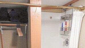 Casa de banho com chuveiro, porta-toalhas e saco para roupa com a etiqueta 'roupa suja'.