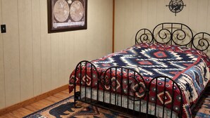 Quarto com cama, bússola fixada na parede e mapa emoldurado.