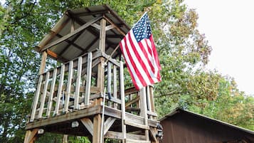 Une tour d’observation en bois, surmontée d’un drapeau américain, entourée d’arbres.