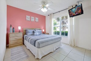 A bedroom with a bed, bedside tables, a ceiling fan, a TV, and a window with curtains. - Oakhill - Fairytale Villa 10 Mins From Disney (Kissimmee)