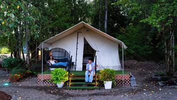 A tent with a covered porch, two chairs, and potted plants.
