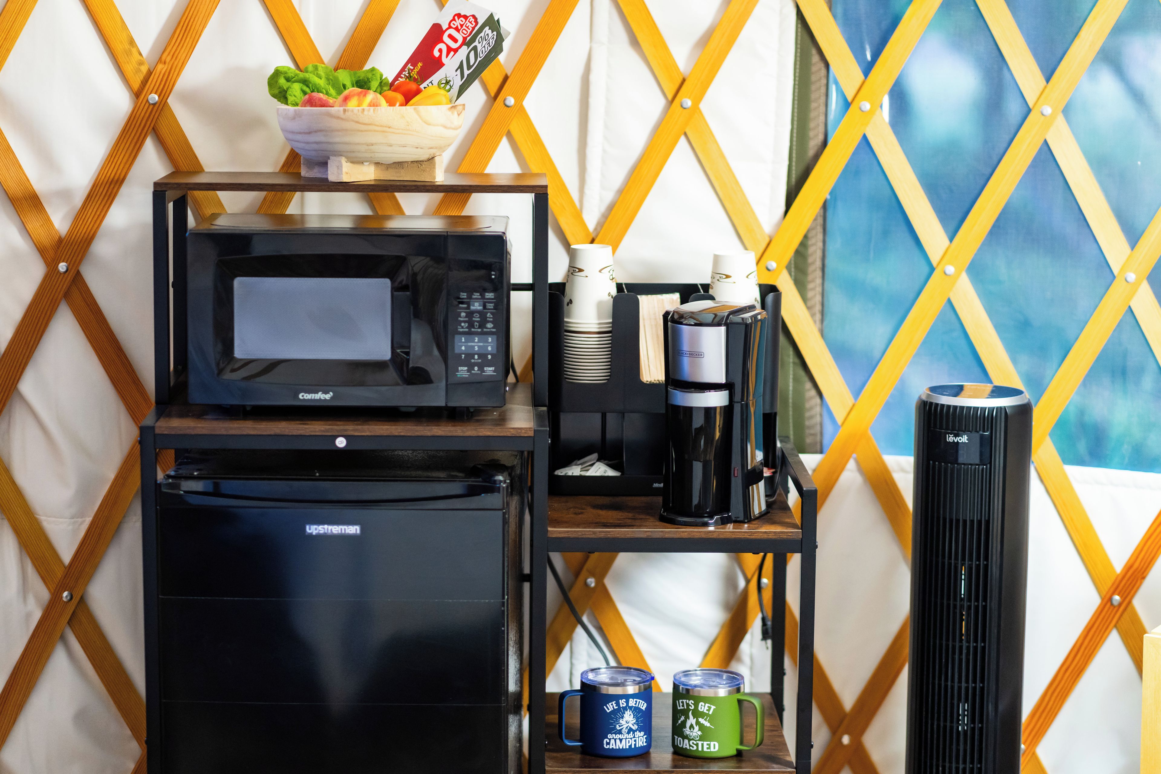 Een kitchenette met een magnetron, koffiezetapparaat en een koelkast.