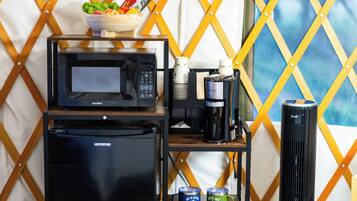 Een kitchenette met een magnetron, koffiezetapparaat en een koelkast.