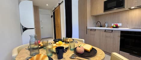 A modern kitchen with wooden cabinets, a microwave, and a dining area with a table set for breakfast.