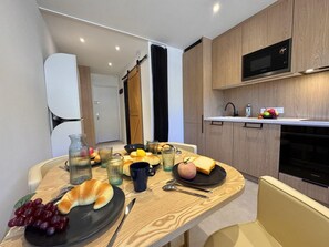 Cozinha moderna com armários de madeira, micro-ondas e área de jantar com mesa posta para o café da manhã.