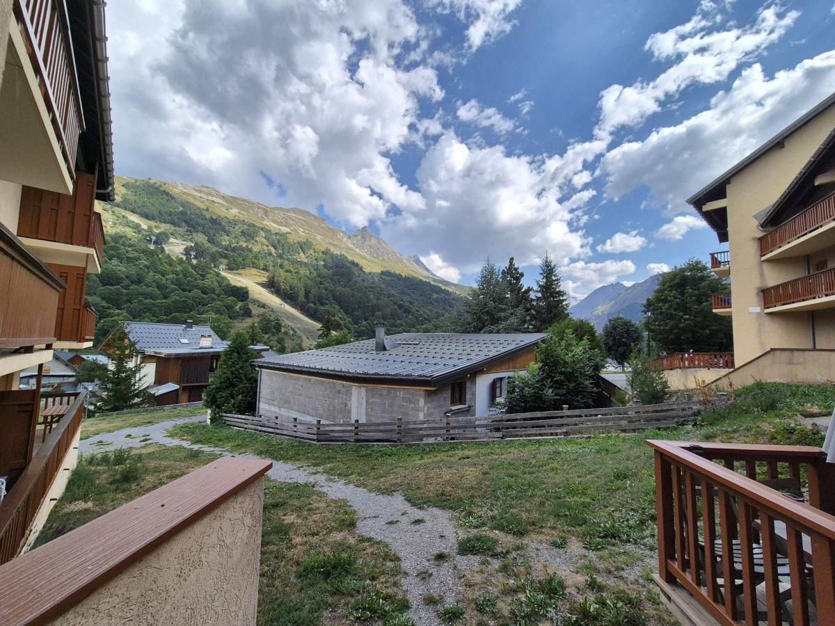 A mountainous landscape with a building that has a sloped roof and a wooden fence in the foreground.