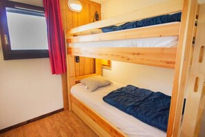 A bunk bed with a wooden headboard, a bedside table with a lamp, and a window with curtains. - 300m from ski slopes, 1st floor, balcony, parking, tv, ski locker, 45m², La Norma (Villarodin-Bourget)