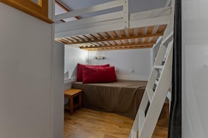 A compact room with a bunk bed, a small wooden table, and a window. - 40m from ski slopes, 2nd floor, fitness, swimming pool, sauna, balcony, tv, ski locker, 34m² (Les Orres)