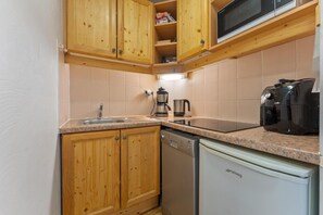 A compact kitchen with wooden cabinets, a microwave, a coffee maker, and a dishwasher. - 40m from ski slopes, 2nd floor, fitness, swimming pool, sauna, balcony, tv, ski locker, 34m² (Les Orres)