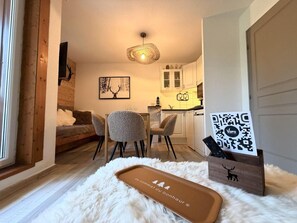 A cozy room with a sofa, chairs, a wooden cabinet, a fluffy rug, and a QR code sign. - 100m from ski slopes, 3rd floor, balcony, tv, ski locker, 27m², Vars (Vars)