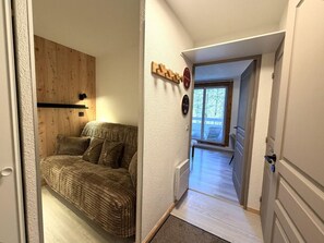 A room with a sofa, a wooden wall panel, a radiator, and a door leading to a balcony. - 100m from ski slopes, 3rd floor, balcony, tv, ski locker, 27m², Vars (Vars)