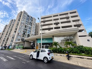 A modern building with a flat facade, a covered entrance, and a car parked in front. - BORA Ventura 104: Your Space Away from Home (Ibagué)