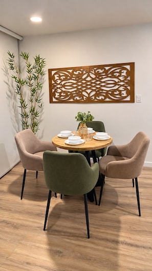 Un comedor con una mesa redonda, cuatro sillas y un panel decorativo en la pared.