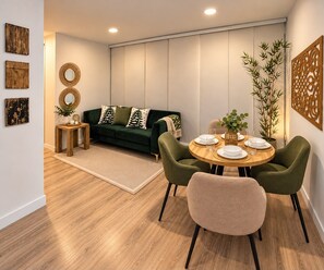 Un soggiorno moderno con un divano verde, un tavolo da pranzo in legno, sedie, un piccolo tavolino e decorazioni alle pareti.