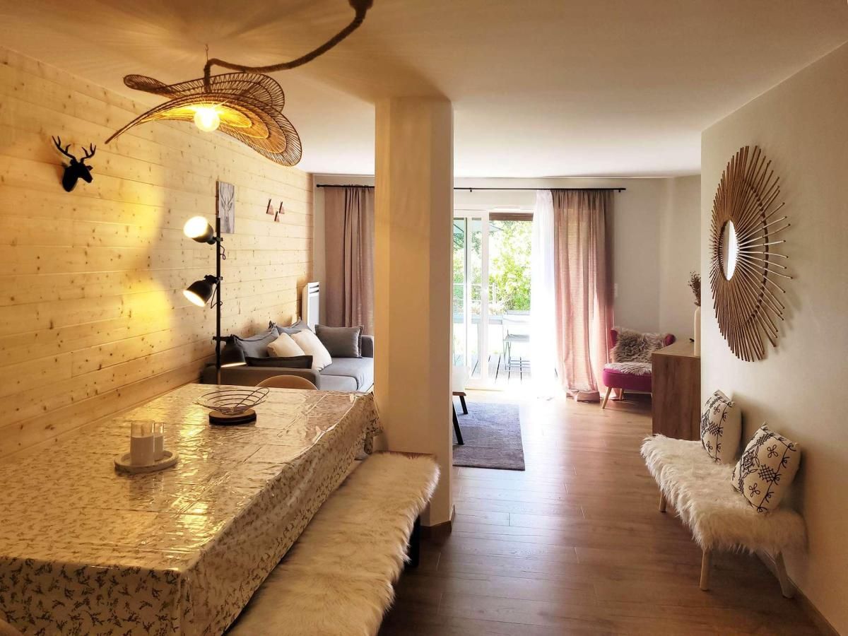 A room with a wooden wall, a sofa, a bench, a table with a lamp, and a decorative mirror.