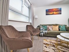 Una sala de estar con un sofá, dos sillones, una mesa de centro y un cuadro en la pared.