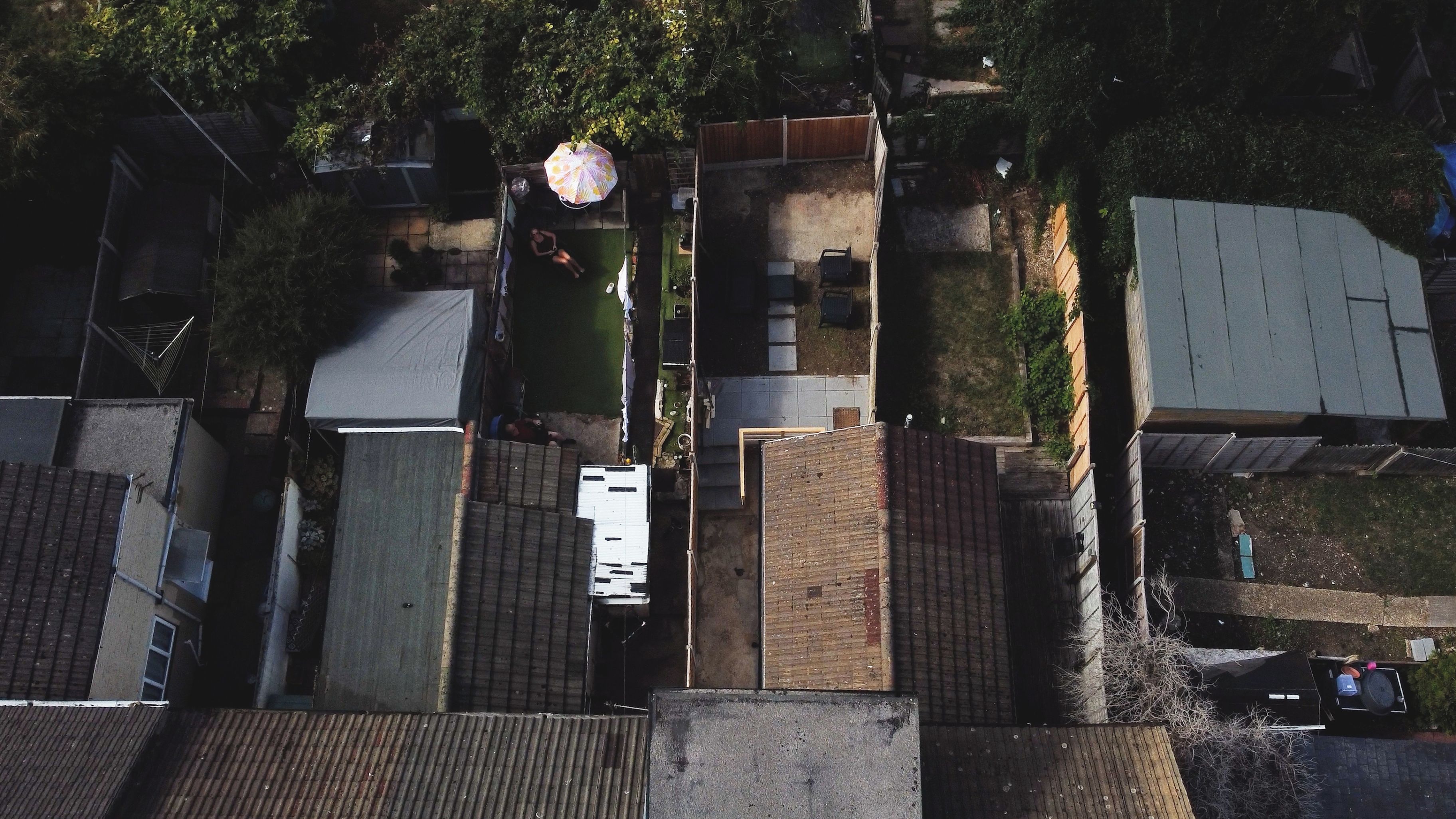 Ett flygbildsbild av ett bostadsområde med flera hus, en inhägnad trädgård och en liten trädgård.