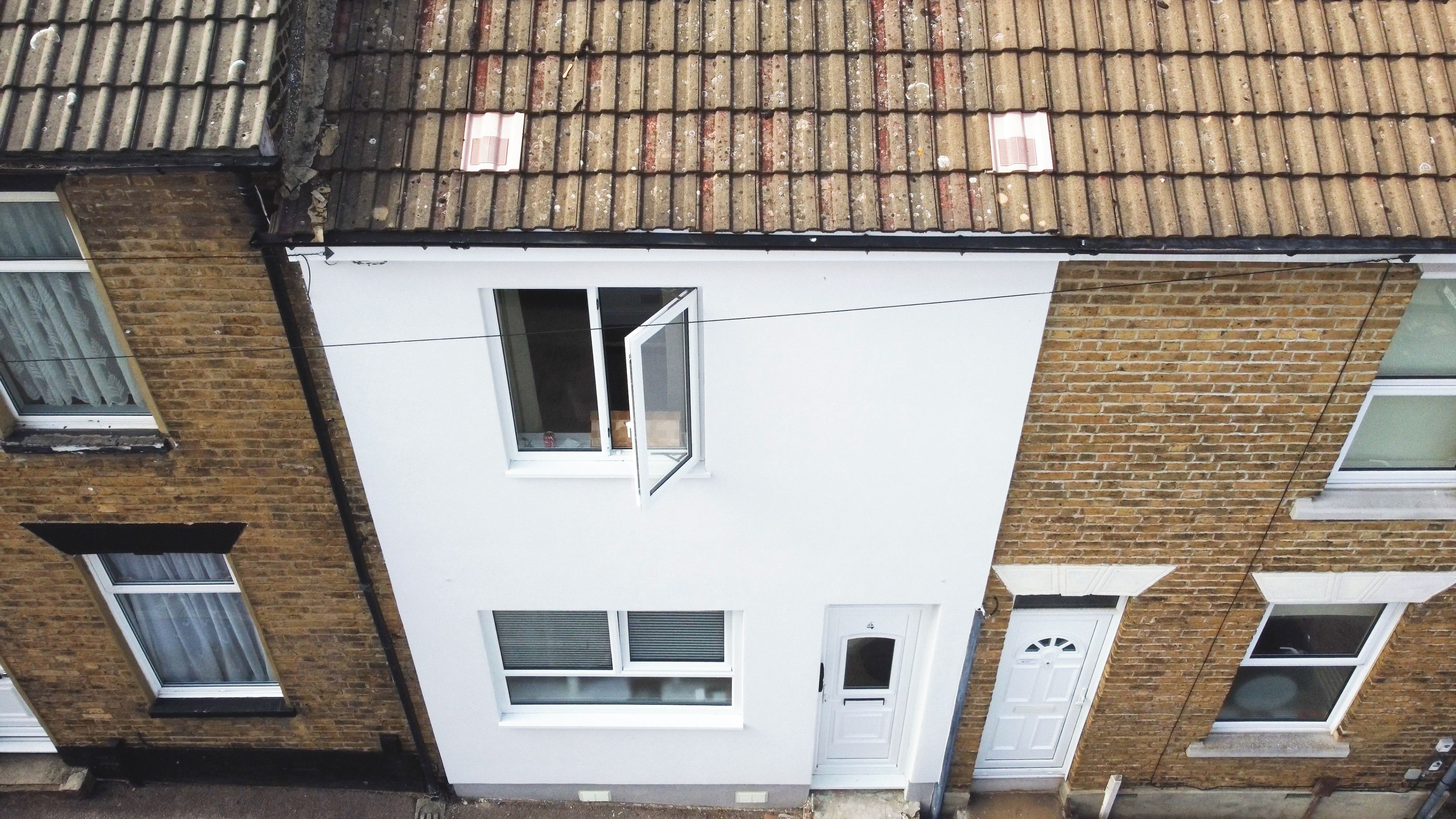 A residential building with a white facade, multiple windows, and a tiled roof.