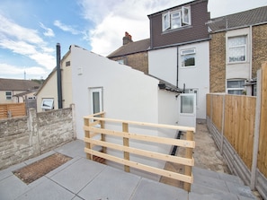 A residential area with a white house, a wooden fence, and a brick pathway.