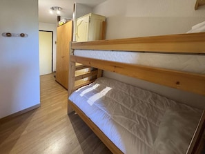 A bunk bed with a wooden frame and a white mattress in a room with wooden flooring and a door in the background. - 40m from ski slopes, 2nd floor, balcony, 19m², Les Orres (Les Orres)
