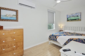 Een slaapkamer met een bed, dressoir, airconditioning en wanddecoratie.