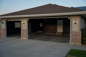 A two-car garage with a covered driveway and a brick exterior. - Luxury Bluffdale Retreat Theater•Hot Tub •Sauna (Bluffdale)