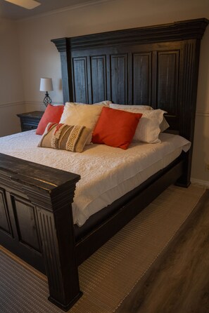 A bedroom with a dark wooden bed frame, white bedding, and multiple pillows in various colors. - Luxury Bluffdale Retreat Theater•Hot Tub •Sauna (Bluffdale)