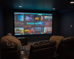 A home theater with a large screen displaying movie options. - Luxury Bluffdale Retreat Theater•Hot Tub •Sauna (Bluffdale)
