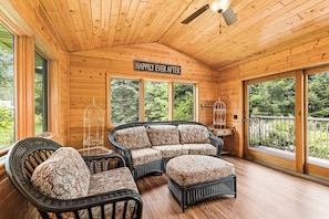 A wooden interior with a ceiling fan, a sign reading 'HAPPILY EVER AFTER', and a seating area with wicker furniture.