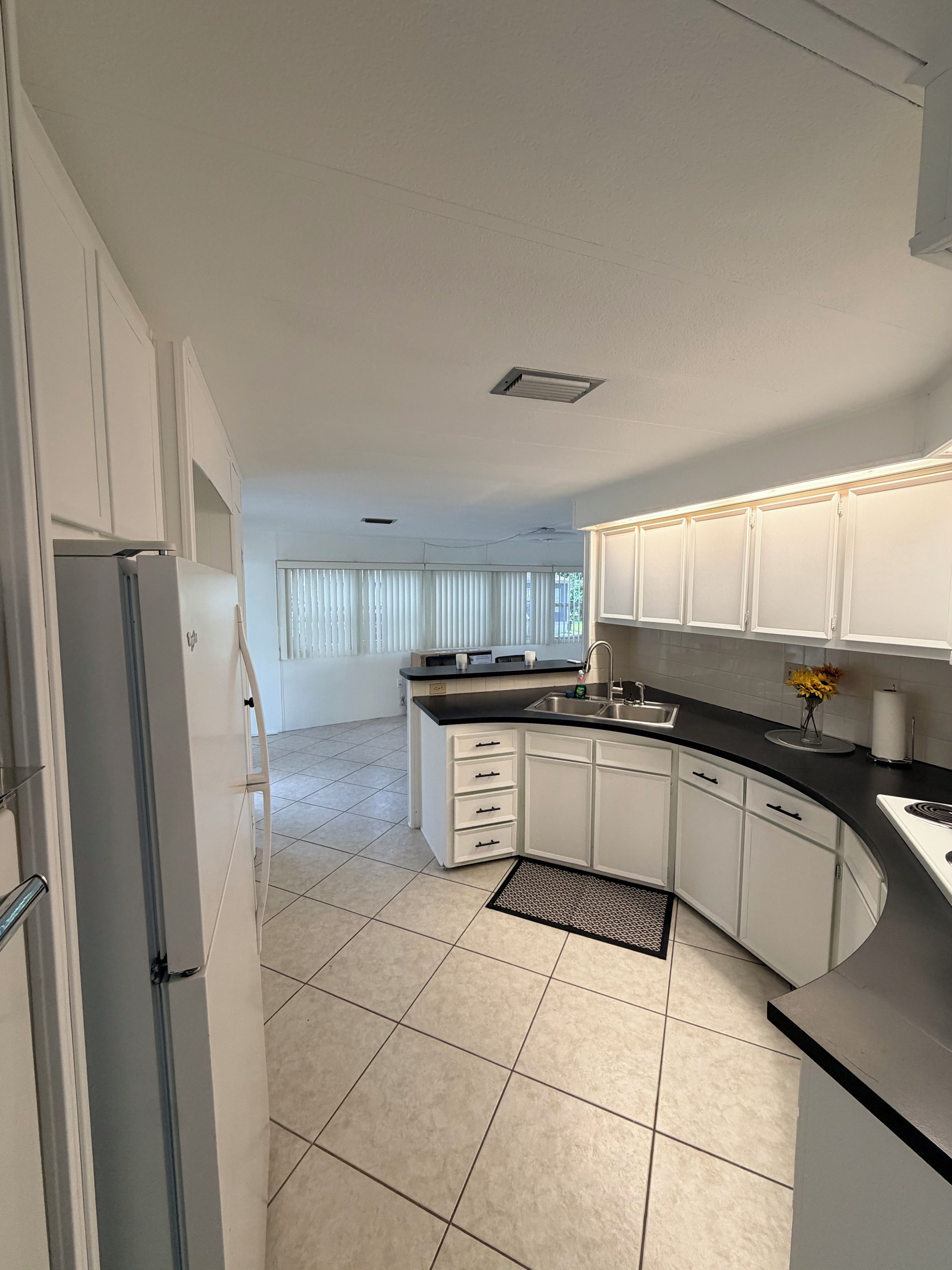 A modern kitchen with white cabinets, a black countertop, and a stainless steel sink.