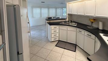 A modern kitchen with white cabinets, a black countertop, and a stainless steel sink.
