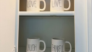 Un mueble con tres tazas blancas, cada una con una palabra escrita.