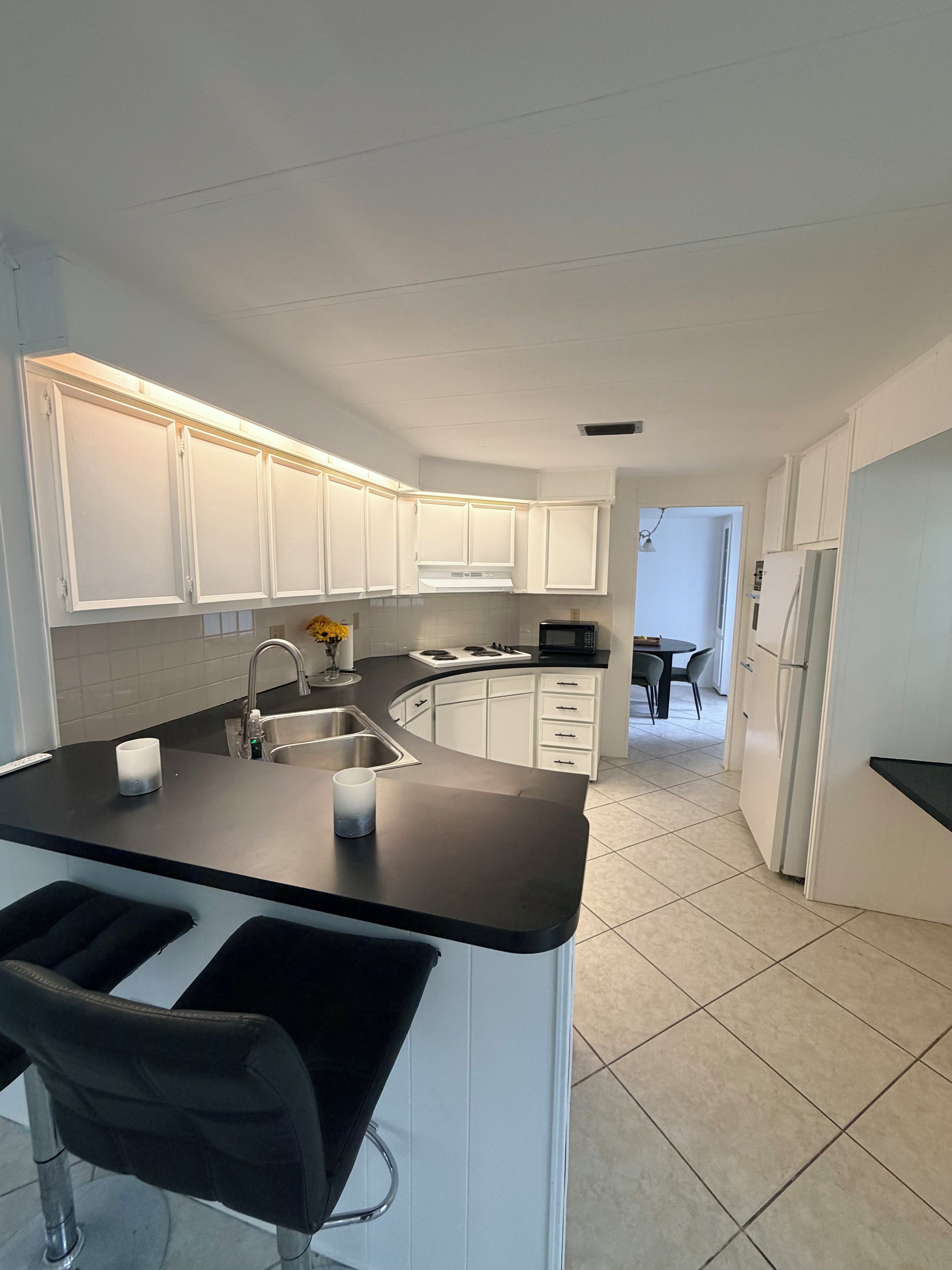 A modern kitchen with white cabinets, a black countertop, and a stainless steel sink.