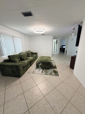 A living room with a sofa, ottoman, and a ceiling light fixture.