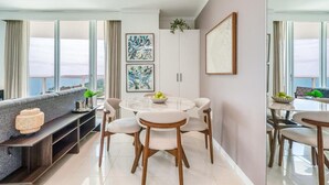 A modern dining area with a round table and chairs, a sofa, and artwork on the walls. - Bay View Beauty: 1/1.5 Bath Condo in Coconut Grove! Parking Included (Miami)