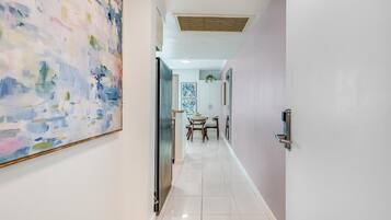 A hallway with a dining area, a large abstract painting, and a door with a handle.