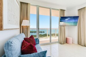Une chambre d’hôtel avec un canapé, une télévision, une lampe et une vue sur la mer.
