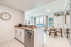 Une cuisine moderne dotée d’un lave-vaisselle encastré, d’un grand îlot central avec un évier et d’un coin repas comprenant une table et des chaises.